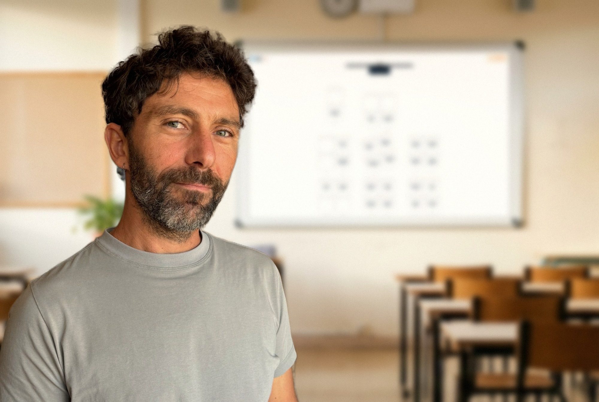 Benjamin Taisne, professeur de mathématiques, dans une salle de classe ; derrière lui, le plan de classe Oléo projeté au tableau pour les élèves.